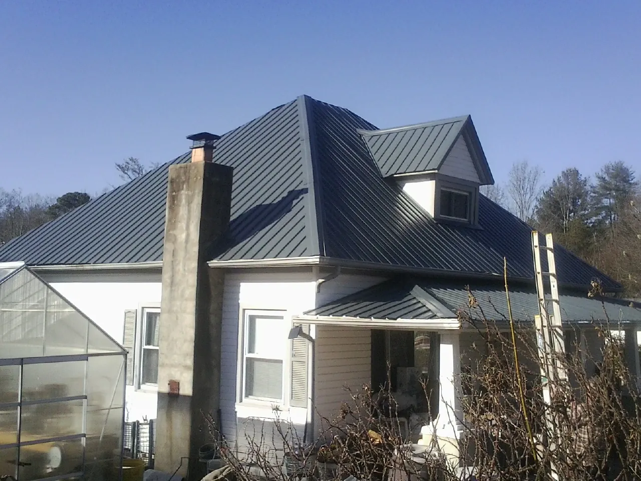 Dark blue standing seam metal roof on a white farmhouse with dormer — Slate & Tile Roof Repair by Roofing Brothers in Barnegat