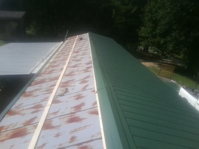 Old rusted panels beside newly installed green metal roofing — Wind Damage Roof Repair by Roofing Brothers in Barnegat