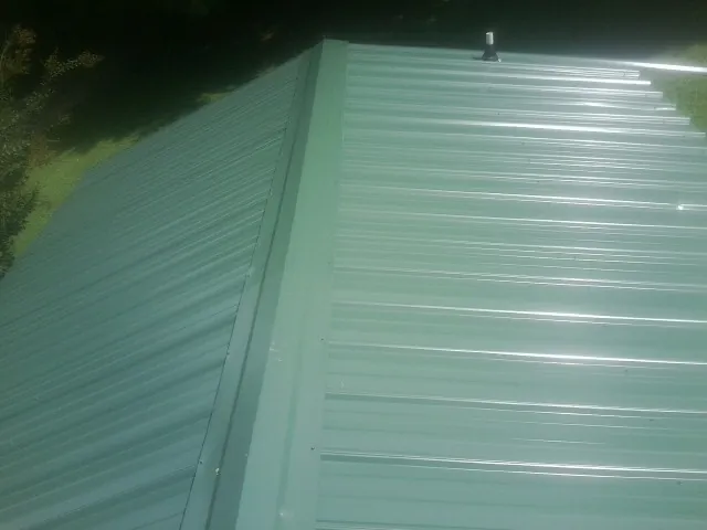 New green metal panels meeting at the ridge of a roof — Flat Roof Repair work by our crew in Barnegat