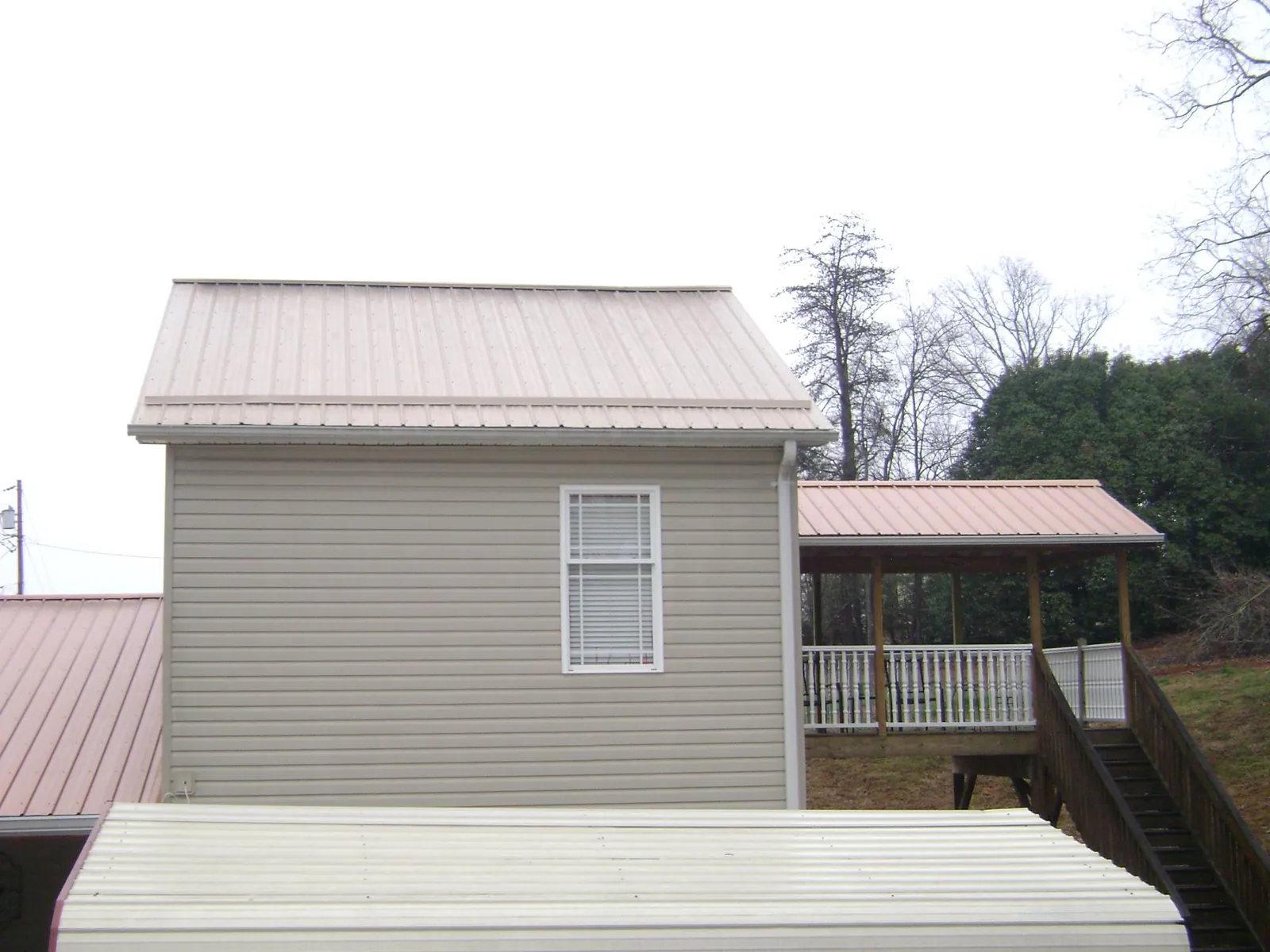 Tan metal roofs on a two story addition and attached porch, from a Roof Replacement job in Barnegat