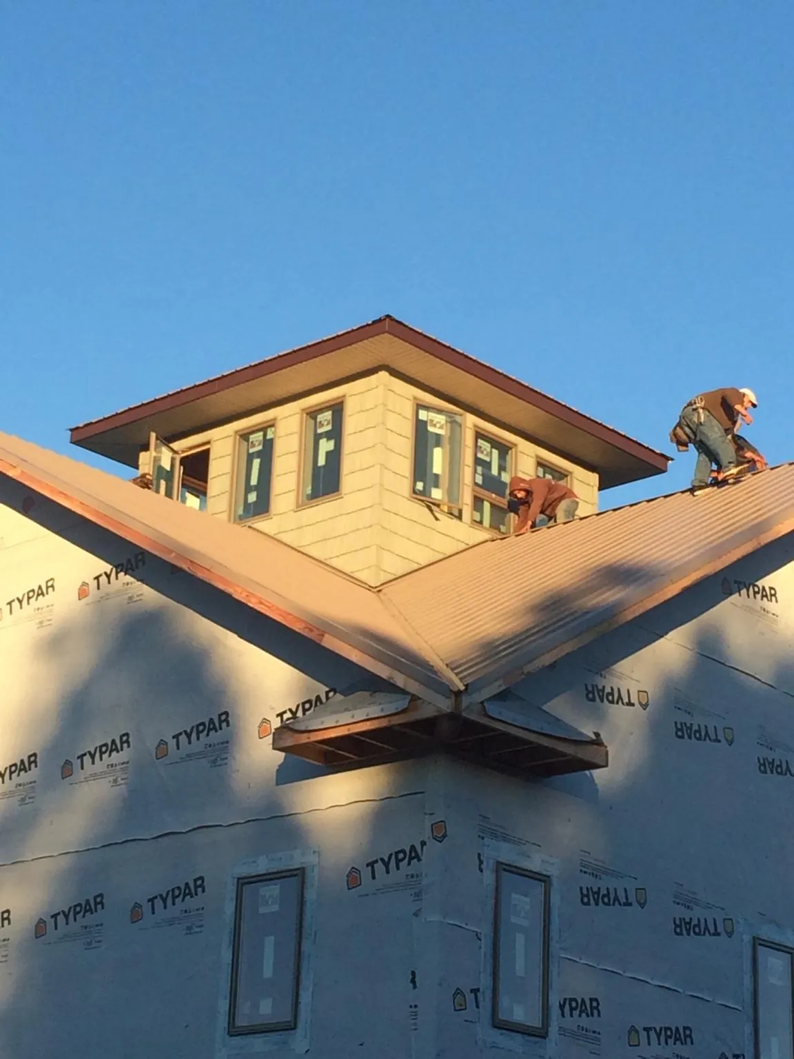 Roofers working around a rooftop cupola on a new metal roof at sunset — Roof Waterproofing in Barnegat by Roofing Brothers
